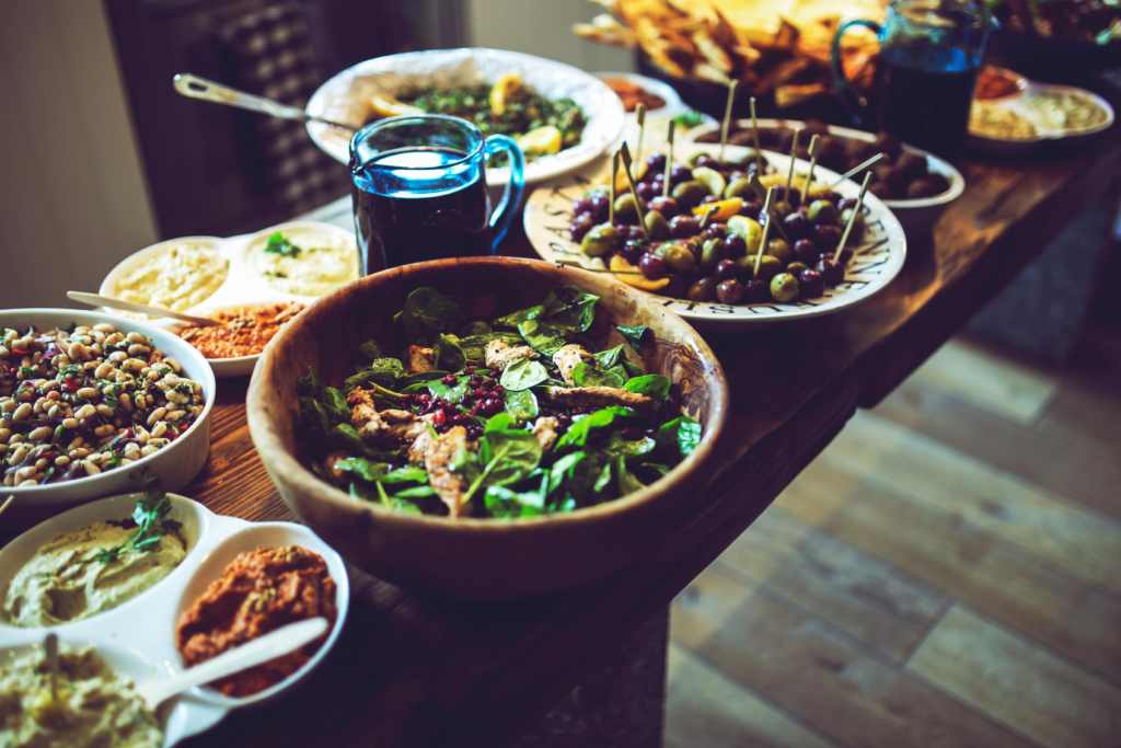 Mediterranean antipasti featuring olives, spinach salad, and dips on a rustic wooden table.